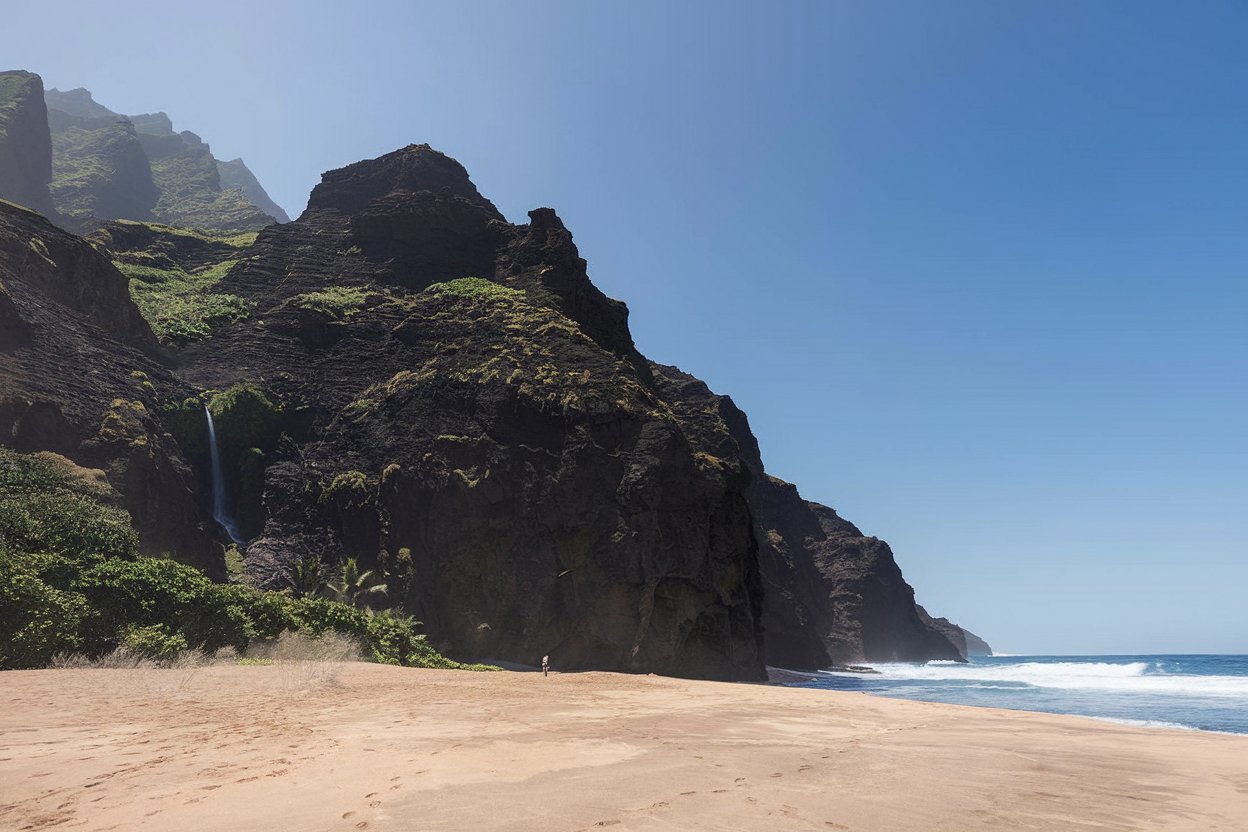 pristine beach along the kalalau trail in hawaii, united states, with golden sands, rugged green cliffs, a cascading waterfall, and the pacific ocean stretching to the horizon